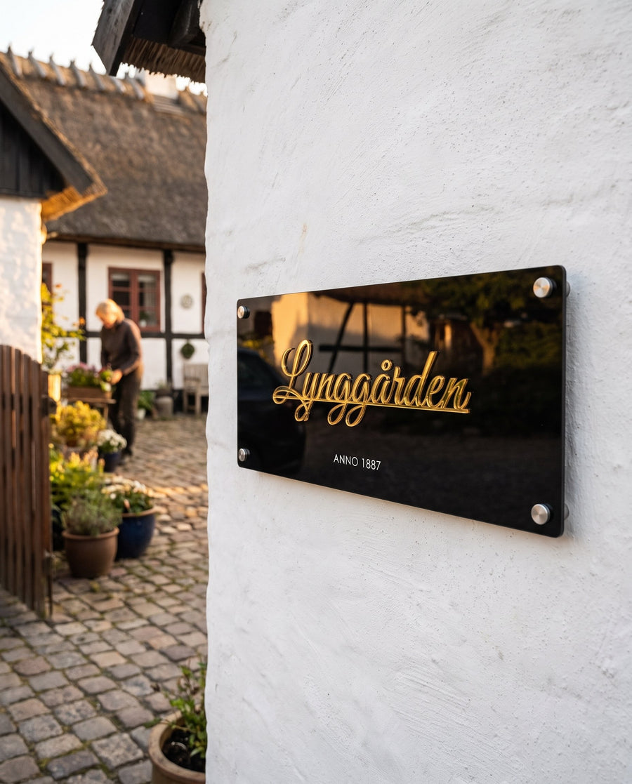 Hede: gårdskilt i sort akryl med gårdens navn i guld og årstal – i brug