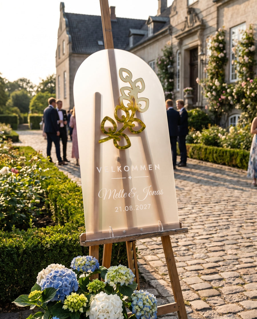 Odde: højt velkomstskilt til bryllup i frosted akryl med eukalyptus i guld – i brug