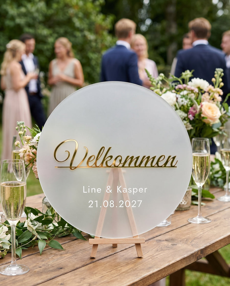 Kyst: rundt velkomstskilt i akryl med »Velkommen« i guld, Ø 300 mm – i brug